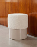 HELVIS upholstered stool featuring a rounded textured seat and smooth cylindrical base. Its refined proportions and tactile materials create a versatile accent for residential and hospitality interiors.