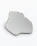 Sculptural LAB M wall mirror featuring an irregular organic silhouette and slim light-toned frame. The asymmetrical form combines functional reflection with a distinctive contemporary aesthetic.
