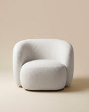 Sculptural LYSA lounge chair featuring a fully upholstered rounded shell, enveloping armrests, and a generously cushioned seat. Its soft organic silhouette creates a refined contemporary seating piece.