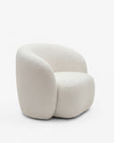LYSA lounge chair with a deep upholstered seat, rounded backrest, and sculptural enveloping sides. The tactile upholstery and fluid silhouette emphasize comfort and contemporary craftsmanship.