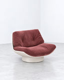Lalea lounge chair featuring a sculptural burgundy upholstered seat and curved backrest above a rounded pedestal base. The rich color and fluid contours create a distinctive contemporary seating piece.