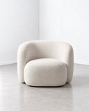 Lysa lounge chair featuring a fully upholstered ivory shell, rounded armrests, and a deep cushioned seat. Its enveloping form and soft texture create a refined contemporary accent chair.