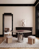 Sculptural ORBITAE dining table combining a round burgundy stone tabletop with a polished cylindrical metal base. Its elegant proportions make it a distinctive statement piece for contemporary dining interiors.