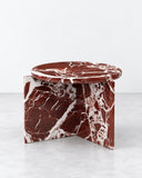 Origin side table featuring a richly veined burgundy stone top and a substantial sculptural stone base. The monolithic construction and natural patterning create a distinctive contemporary accent table.