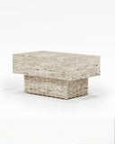 Sculptural THERRA side table crafted from light travertine with a thick rectangular top and solid pedestal base. The monolithic stone construction highlights the material's natural texture and contemporary form.