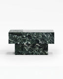 THERRA side table featuring a richly veined green stone top and solid geometric pedestal base. Its compact monolithic form showcases the natural variation and depth of the stone.