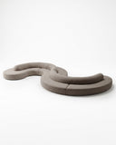 Sculptural TRACE MODULAR sofa composed of interconnected curved upholstered modules arranged in an organic configuration. The flexible seating system combines soft geometry with contemporary modular design.