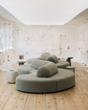 Sculptural modular sofa composed of curved upholstered sections with rounded backs and generous cushions. Its organic configuration creates a soft architectural presence in contemporary interiors.
