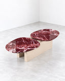 SECOLO Taras Coffee Table combining two burgundy marble tops with dramatic white veining and a contrasting light-toned connecting base. Its elongated sculptural composition makes a distinctive statement in contemporary living spaces.