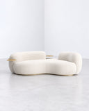 Tateyama Sofa featuring a sculptural, low-profile silhouette with softly curved ivory upholstery and integrated gold-tone side tables. Its fluid, organic form and refined detailing make it a distinctive statement piece for contemporary luxury residential and hospitality interiors.