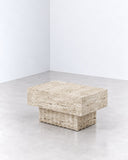 Therra side table featuring a compact rectangular travertine top and solid geometric stone supports. Its natural texture and low sculptural profile create a contemporary accent with understated material character.