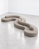 Trace Modular sofa featuring interconnected curved upholstered sections arranged in a flowing serpentine configuration. The modular design combines generous seating with sculptural geometry for contemporary residential and hospitality interiors.