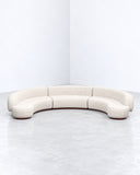 Yamata sofa featuring a curved ivory upholstered backrest and a continuous low-profile seat with rounded edges. Its fluid silhouette and soft neutral finish create a refined contemporary seating piece.