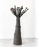Sandrine Herlin Baobab Noir Medium Lighting features a tapered charcoal-grey body with a richly textured surface, small perforations, and branching black stems tipped with warm orange details. Its tree-inspired sculptural form combines earthy textures with a distinctive contemporary lighting aesthetic.