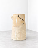 Sandrine Herlin Baobab Side Table features a compact, tapered ivory form with an irregularly textured surface, decorative perforations, and a small integrated side handle. Its sculptural vessel-like silhouette and handcrafted appearance bring distinctive character to contemporary interiors.