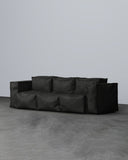 Black modular sofa on a gray floor with a plain white wall background
