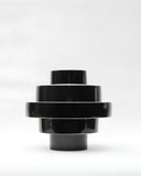 Montée sculptural vessel in glossy black with tiered geometric forms and a contemporary silhouette. A statement designer object for sophisticated modern interiors.