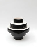 Black Montée sculptural vessel featuring layered cylindrical forms and a glossy finish. Designed as a distinctive decorative object for luxury contemporary spaces.