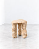 Tellurico 3LEGS Stool featuring a rounded seat supported by three irregular, sculptural legs with a richly textured beige finish. Its organic form and tactile surface give this compact designer stool a distinctive contemporary character.