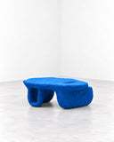 Tellurico La Mesa Coffee Table featuring a low, elongated blue tabletop supported by chunky rounded legs with a continuous sculptural appearance. Its vivid colour, soft geometry, and tactile finish create a playful statement for contemporary living spaces.
