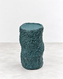 Tellurico Ollain XM Side Table featuring a tall cylindrical form with a rounded top and densely textured blue-grey finish. Its simple vertical silhouette and tactile surface offer a sculptural accent for contemporary interiors.