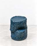 Tellurico Ollain XS Side Table featuring a compact cylindrical silhouette with a distinctive recessed horizontal band and a deep blue textured finish. Its bold surface treatment and geometric form create a contemporary sculptural accent.