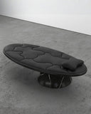 Off Balance Daybed featuring black organic upholstery, a rounded platform and dark marble pedestal base. A sculptural designer daybed for contemporary luxury spaces.