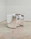 Pill Chair showcasing curved metal panels and a reflective sculptural seat. Designed as a distinctive statement chair for modern interiors.
