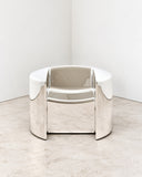 Sculptural Pill lounge chair featuring a rounded upholstered seat, curved backrest, and polished chrome-finish frame with integrated armrests. The fluid silhouette and reflective metal surfaces create a striking contemporary accent chair.