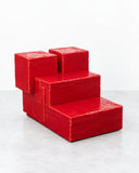 YONT Archetypes Seat featuring a bold, stair-like composition of stacked red geometric blocks with a textured finish. Its architectural silhouette and monolithic form create a sculptural statement in contemporary interiors.