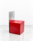 YONT Küp Chair featuring a compact cube-like red seat with a textured finish and a tall, contrasting metallic backrest. Its sharp geometric silhouette and bold material contrast create a distinctive contemporary accent chair.