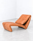 de Sede Yoga Lounge Chair featuring warm cognac leather upholstery, an elongated reclining seat, and a fluid, angular profile with integrated cushioning. Its ergonomic silhouette and rich leather finish combine relaxed comfort with sculptural contemporary design.