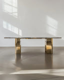 Gold dining table in a minimalistic room with white walls and floor.