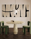 Dining room with a round marble table and green chairs, featuring abstract art on the wall.