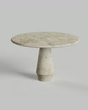 Round marble table with a single pedestal base on a light gray background