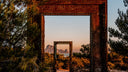 Wooden frame with a scenic view of mountains and sea through it, surrounded by trees.