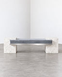 CoExist bench featuring a pale Carrara marble seat with subtle grey veining and sculptural stone supports. The natural marble surface and solid construction give the contemporary bench a refined architectural presence.