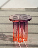 Transparent red resin table casting vibrant warm shadows in a minimalist room