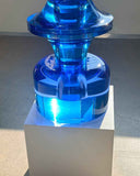 Contemporary blue art object casting colored shadows on a concrete surface